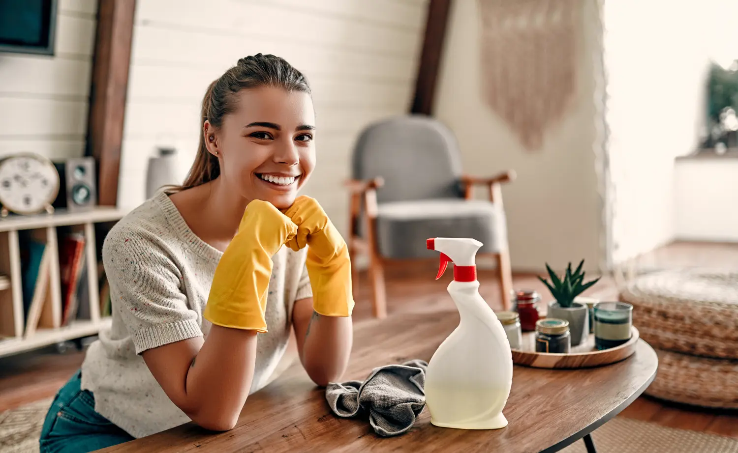 Schöne junge Frau macht das Haus sauber. Mädchen reibt Staub. Frau in Schutzhandschuhen lächelt und wischt Staub mit einem Spray und einem Staubtuch beim Reinigen ihres Hauses.